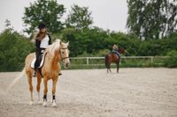 rider-woman-riding-her-horse-on-a-ranch-woman-has-long-hair-and-black-clothes-blurred-second-rider-on-a-horse-on-a-background